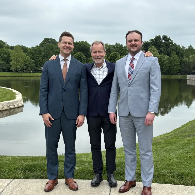A group photo of Nik, Mike, and Matt Lewer in front of a pond.